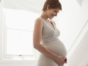 Pregnant woman cradling her belly, representing the importance of folate and vitamins during pregnancy