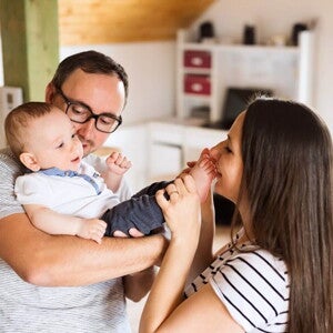 Smiling mother and father holding their newborn baby, symbolizing the potential role of probiotics in supporting male and female fertility beyond digestive health