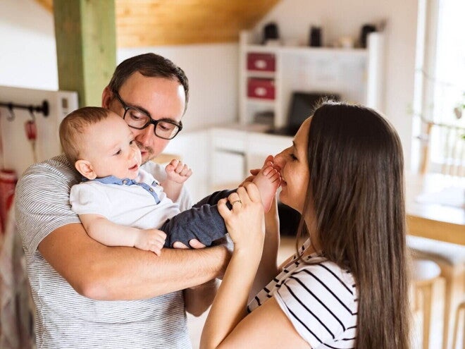 Smiling mother and father holding their newborn baby, symbolizing the potential role of probiotics in supporting male and female fertility beyond digestive health