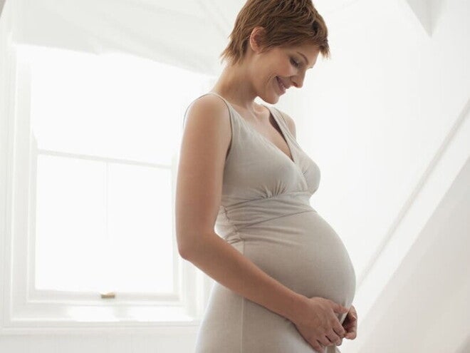 Pregnant woman cradling her belly, representing the importance of folate and vitamins during pregnancy