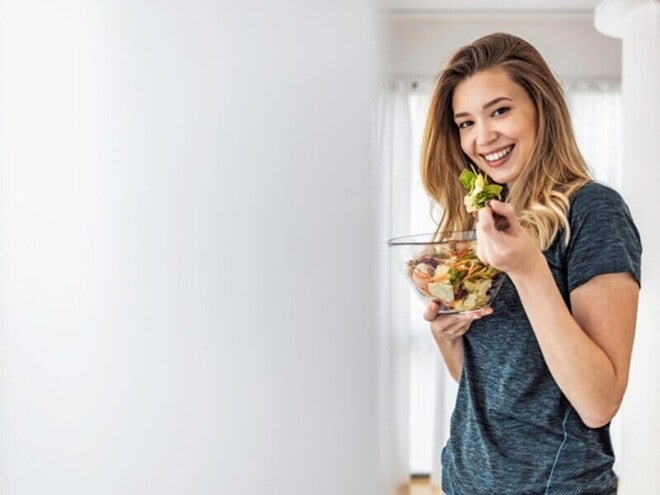 Woman eating a fresh salad, highlighting the role of preconception nutrition in preparing for a healthy pregnancy